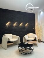Sillas M-3 blancas de Tufá Muebles frente a muro de piedra iluminado